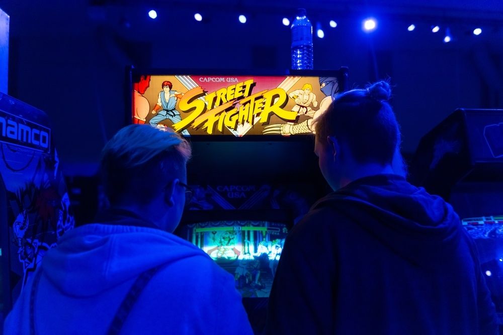Zwei Freunde spielen Street Fighter auf einer Arcade-Maschine