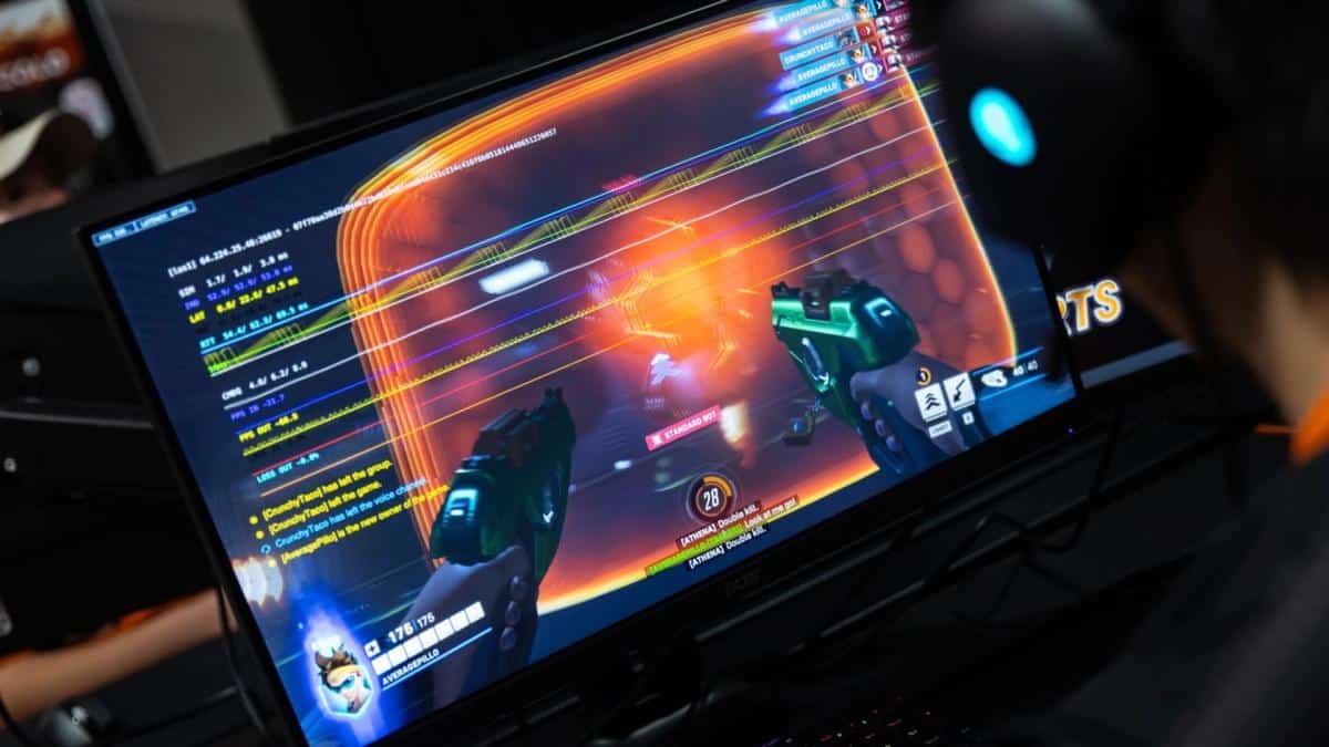 Eine Person mit Headset spielt einen First-Person-Shooter an einem Monitor.