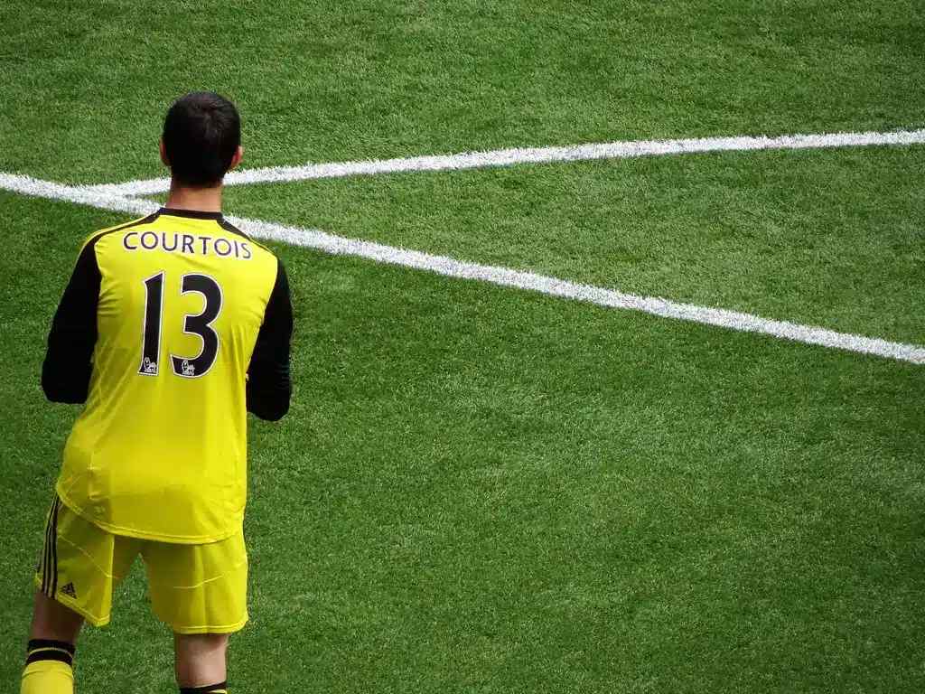 Thibaut Courtois vistiendo una equipación de portero amarilla con el nombre Courtois y el número 13 en la espalda.
