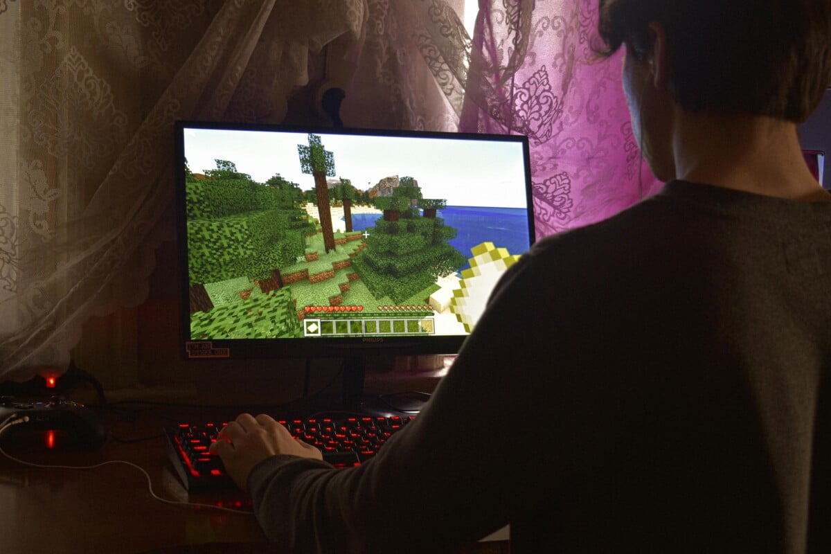 Gamer die achter de pc het populaire spel Minecraft speelt.