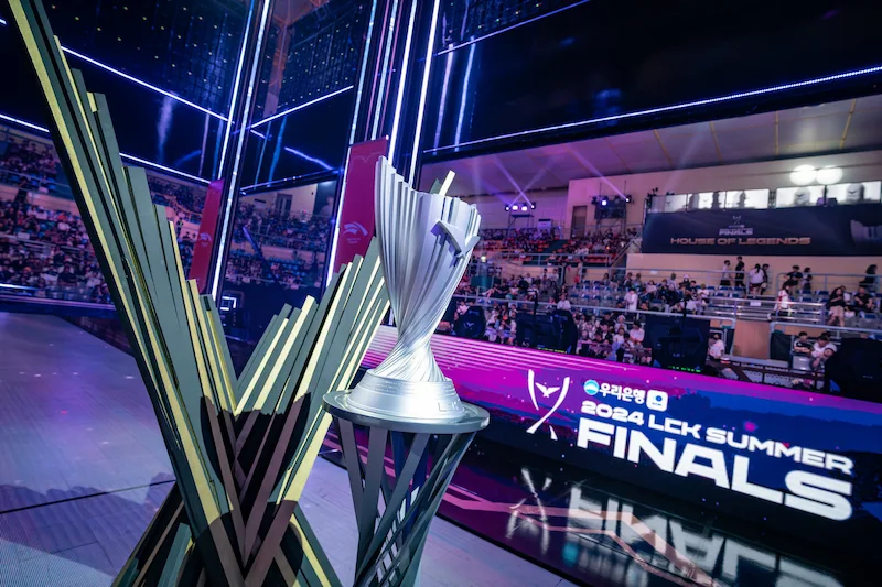 Pokalen för 2024 LCK Summer Finals visas upp på scenen, med en stor publik och neonljus som skapar en spännande atmosfär.