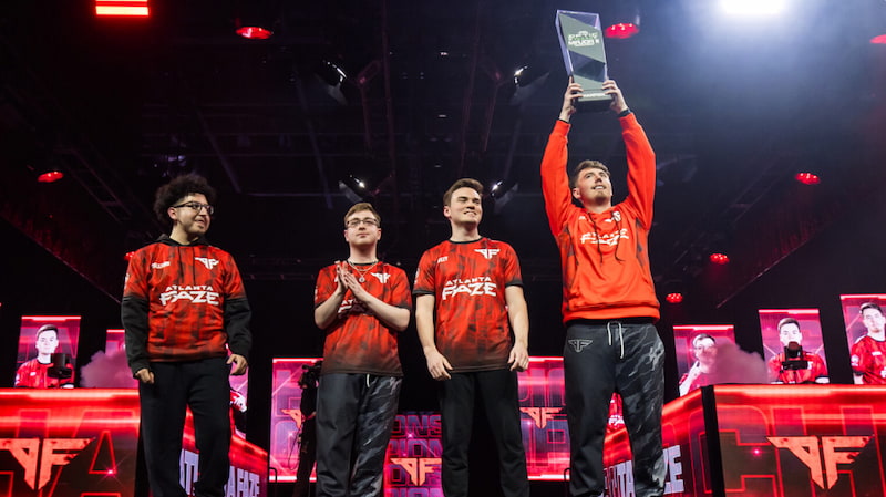 Atlanta FaZe lyfter trofén efter att ha vunnit Major 2 i Call of Duty League, omgivna av lagkamrater på scen.