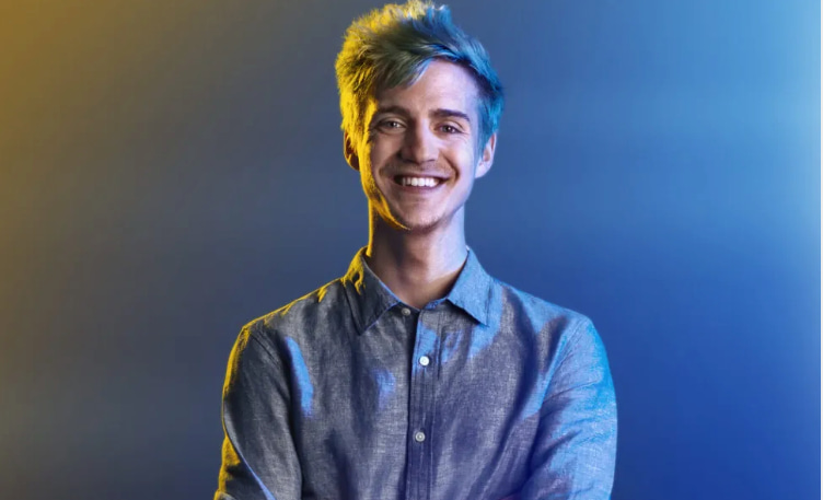 Streamer Ninja med blått hår, klädd i skjorta, mot en bakgrund med blått och gult ljus.