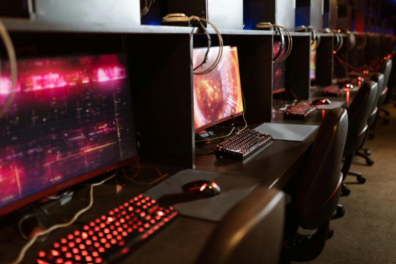 Rader med datorer och speltillbehör i ett modernt gamingcenter eller internetcafé.