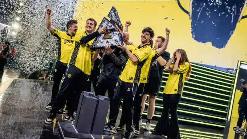 Ett e-sportlag firar seger på scen med pokal och konfetti.
