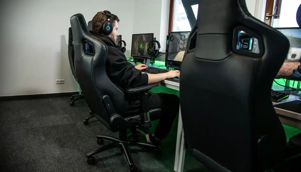 Person sitter vid dator och spelar datorspel i en gamingstol på ett esportcenter.