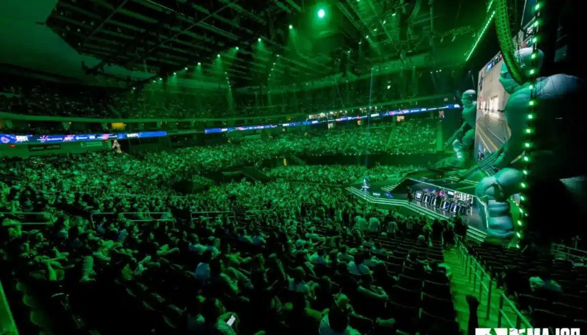 Stor publik tittar på en e-sportturnering i en upplyst arena med scen och stora skärmar.