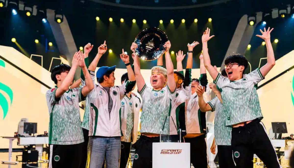 Ett e-sportlag firar sin seger på scenen och lyfter en trofé inför publiken.