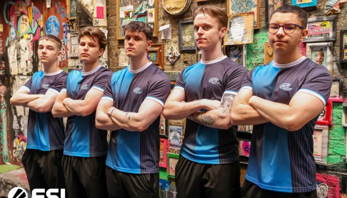 Fem e-sportspelare i lagtröjor poserar med armarna i kors framför en graffitivägg.