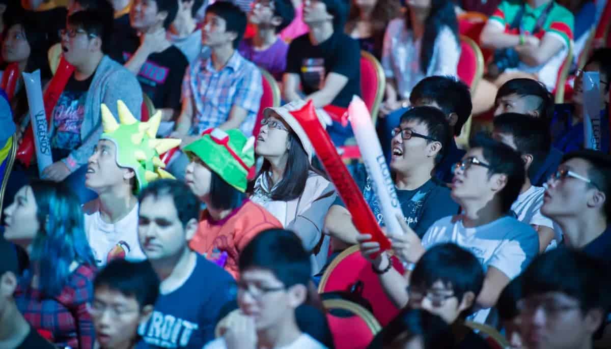 Publik på e-sport­event följer matchen med stort engagemang och färgglada supporterprylar.
