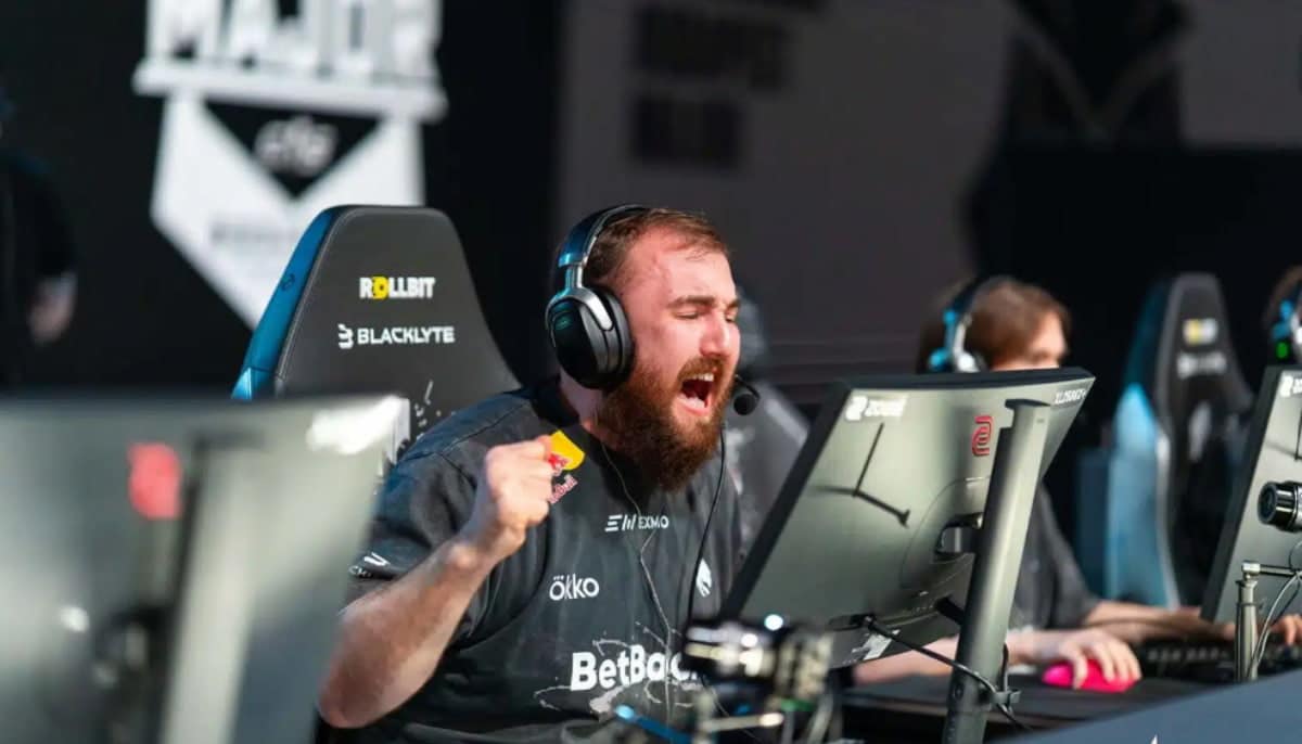 E-sportspelare jublar vid datorn under match med headset och lagtröja