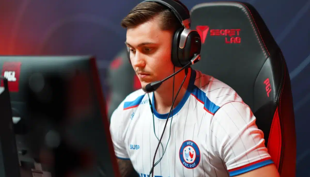 E-sportspelare med headset sitter koncentrerat vid dator under tävling, iklädd matchtröja i gamingarena.