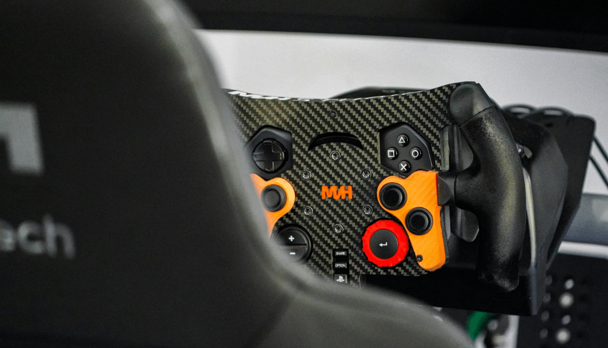 Ratt och knappanel i en simracing-rigg med racingstol i förgrunden och detaljer i kolfiber och orange.