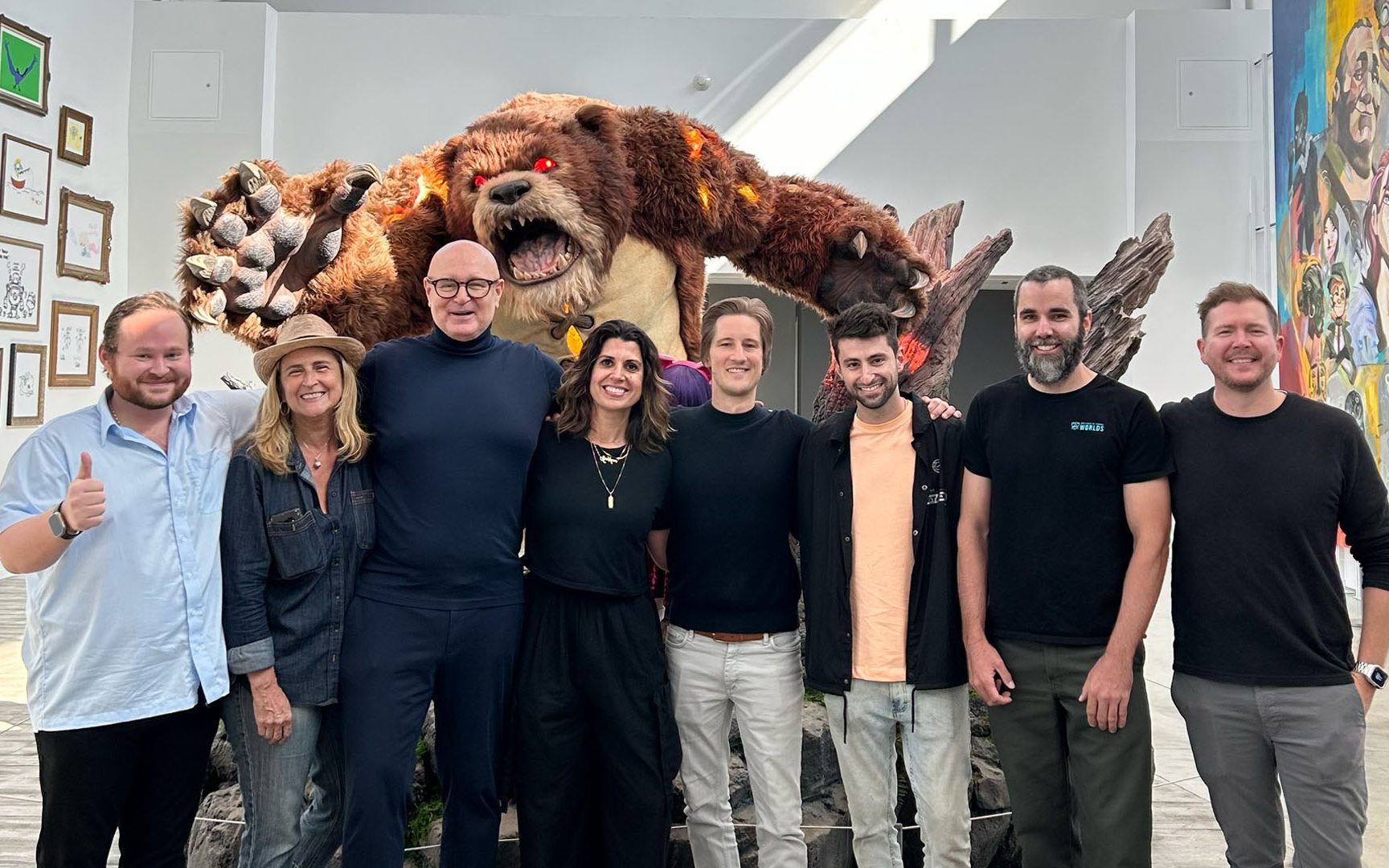 Image of Riot Games and BMG employees stood in front of red-eyed bear