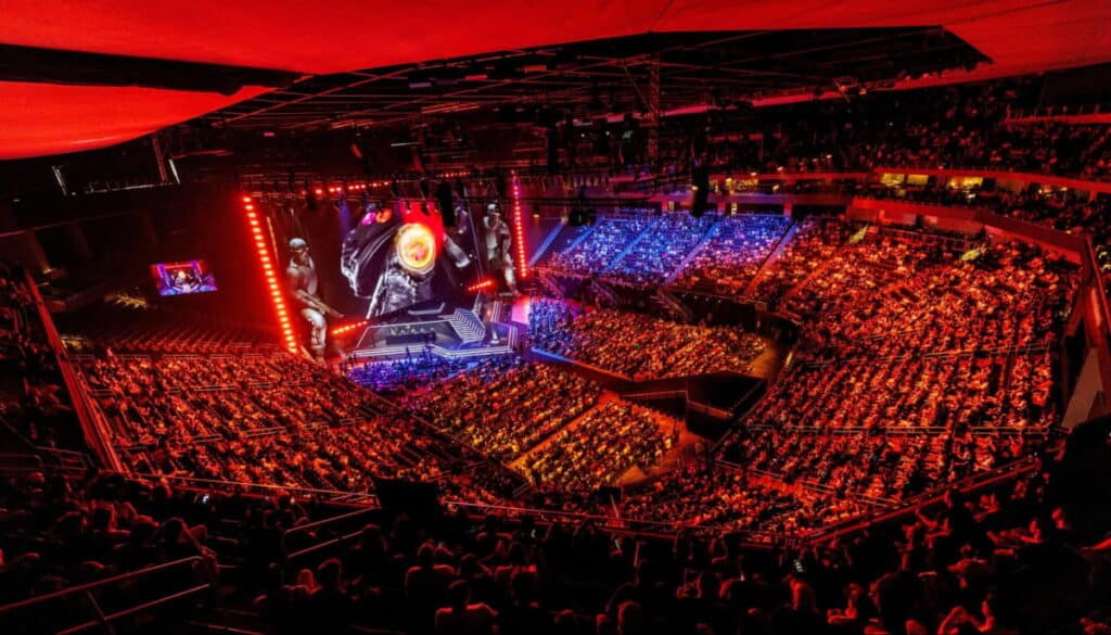 Crowd at a professional esports tournament with a lit stage and game visuals on a large screen