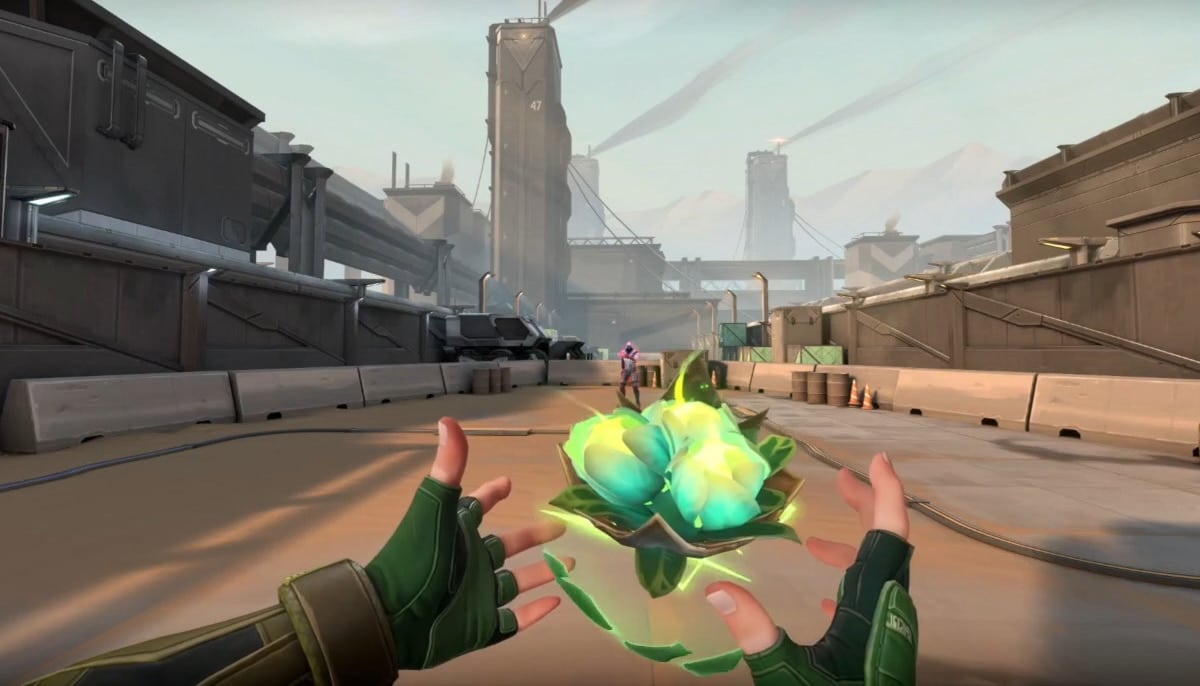 First-person view in VALORANT. Green-gloved hands hold a glowing orb