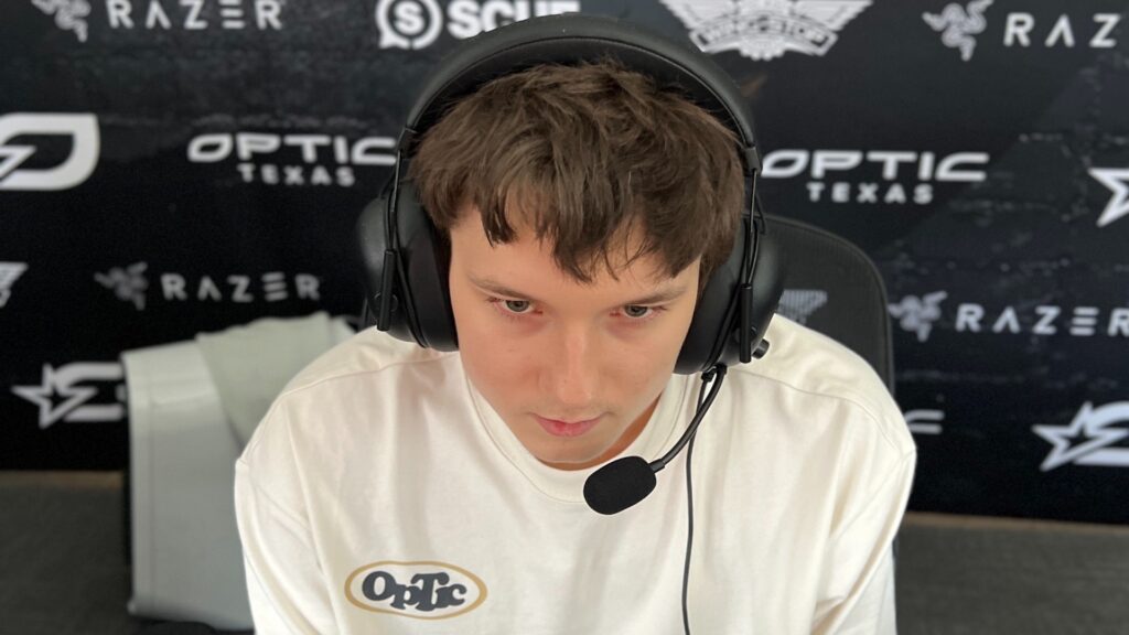 Image of Mercules wearing an OpTic t-shirt. The Optic Texas logo and logs of franchise partners are in the background