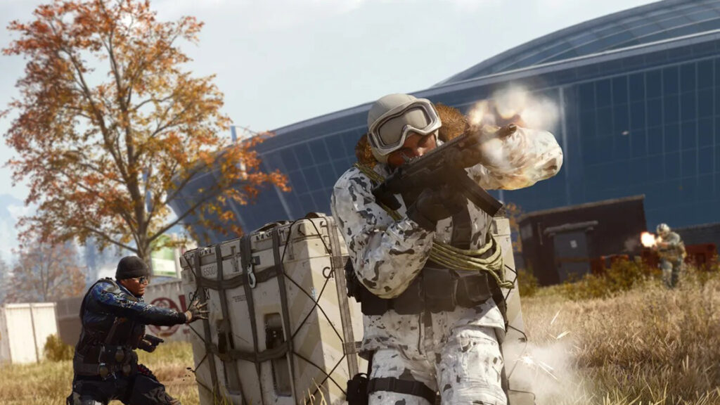 Image of Warzone player firing assault rifle with another player holding a loadout drop. A tree with orange leaves and a blue building is in the background