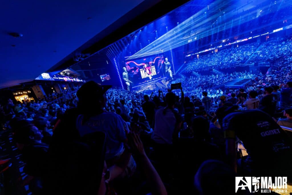 Image of BLAST Austin Major stage illuminated by blue lights with the crowd sitting in darkness