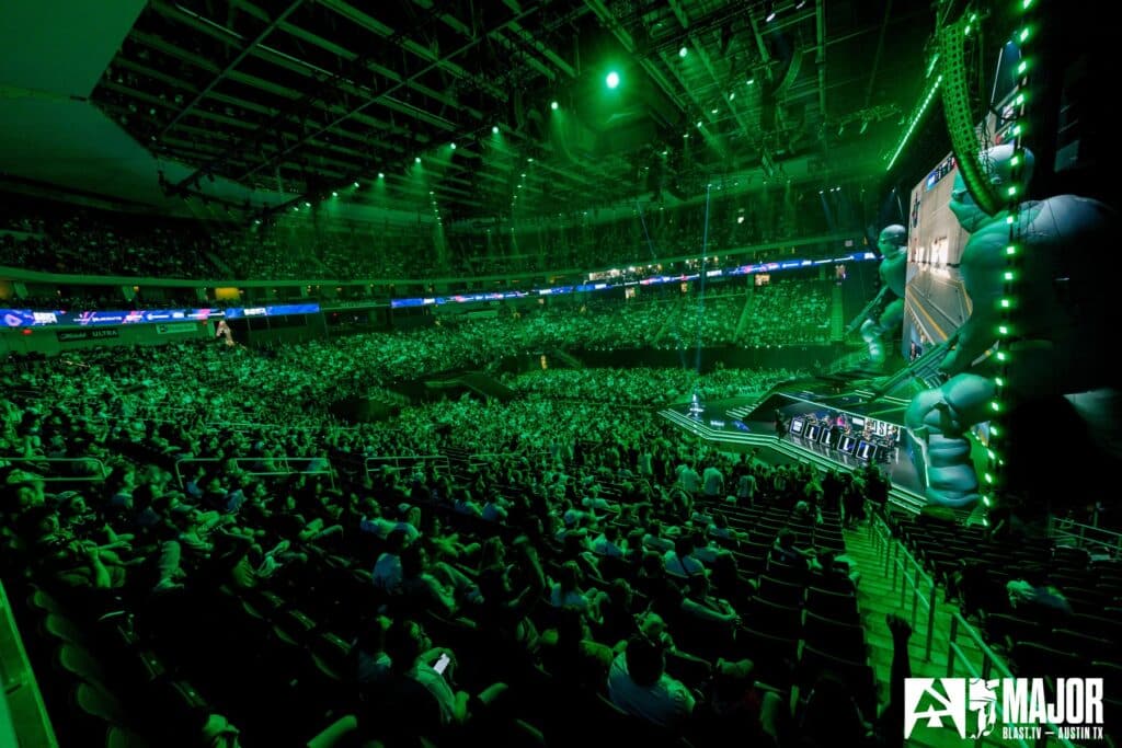 Image of BLAST.tv Austin Major stage and crowd illuminated by green lights from the stage and ceiling