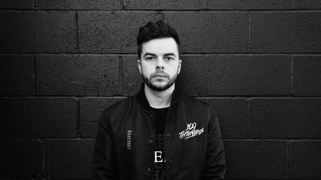 Image of Matt 'Nadeshot' Haag wearing a 100 Thieves jacket while standing against a wall. The image has a black and white filter.
