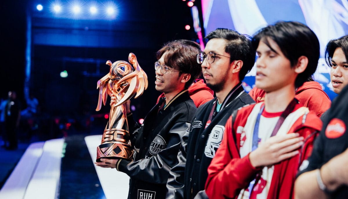 A group of young men stand on stage holding a large, ornate golden trophy
