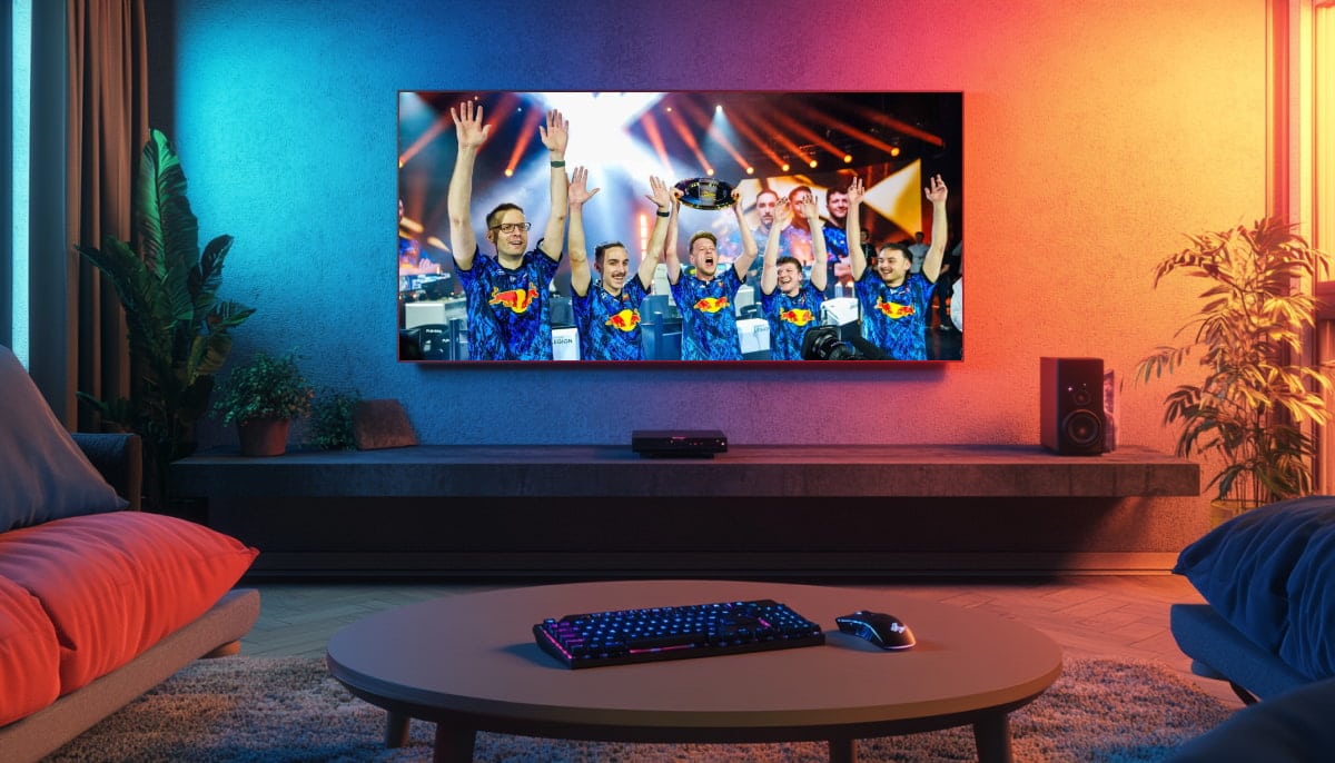 A modern living room features a large TV displaying an excited esports team celebrating with raised hands