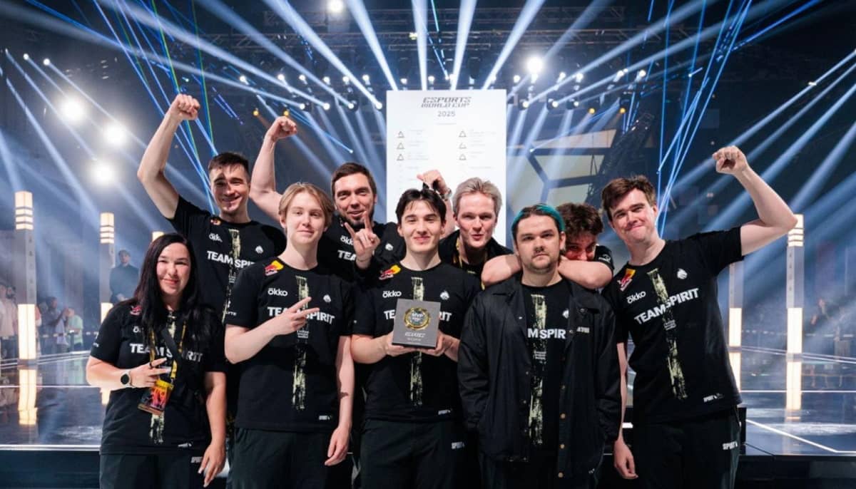 Team Spirit, a group of nine people, celebrates on stage at an esports event
