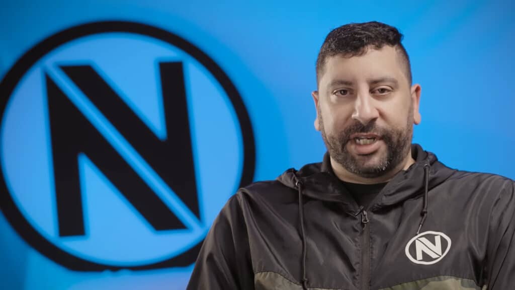 Image of Mike 'Hastr0' Rufail wearing ENVY branded hoodie. A black ENVY logo on a blue wall is in the background