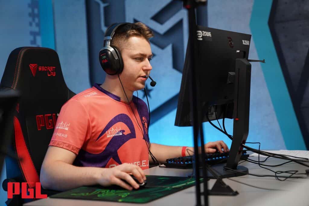 Image of Bymas competing at PGL Counter-Strike event. The player is sitting in front of a monitor holding a mouse and using a keyboard