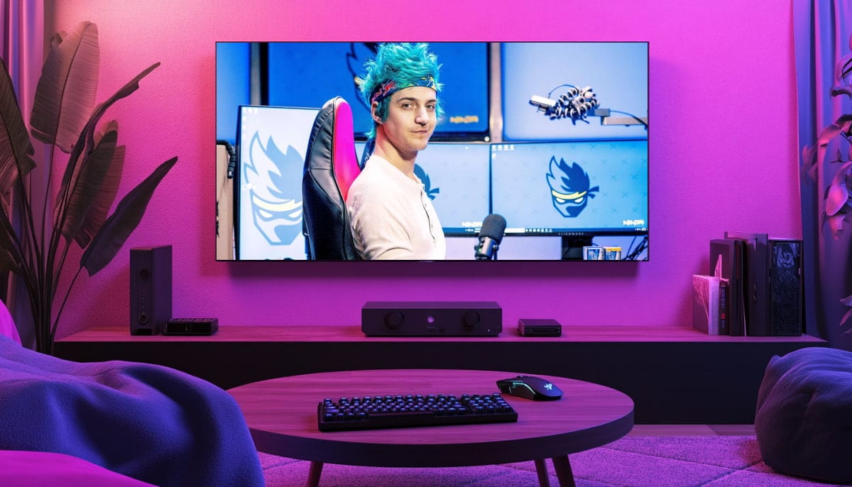 A living room with a large TV displaying a streamer with bright blue hair, smiling