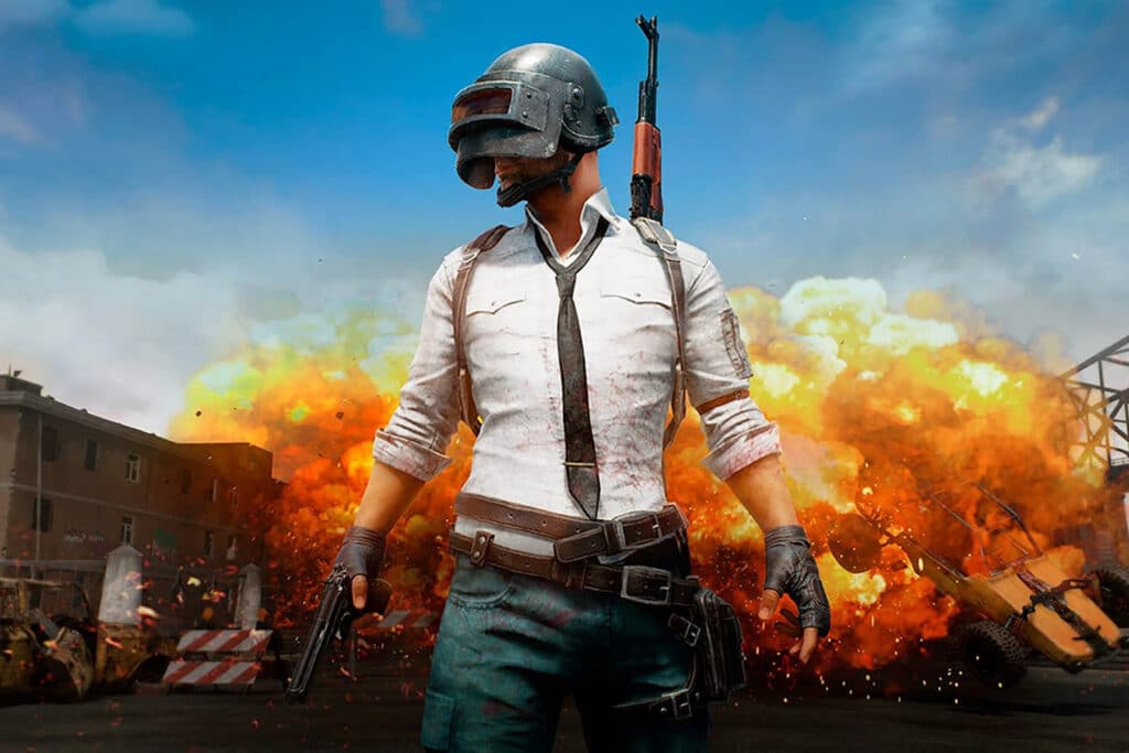 Image of PUBG Mobile player wearing helmet while carrying pistol in hand and an assault rifle on their back. A vehicle is exploding in the background