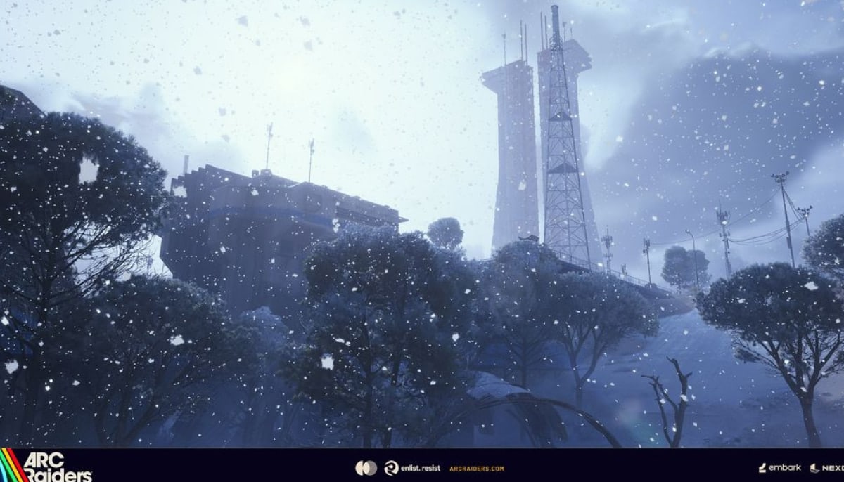 Snow falls gently on a winter landscape with leafless trees, a large building, and two tall communication towers, creating a serene, cold atmosphere in Arc Raiders