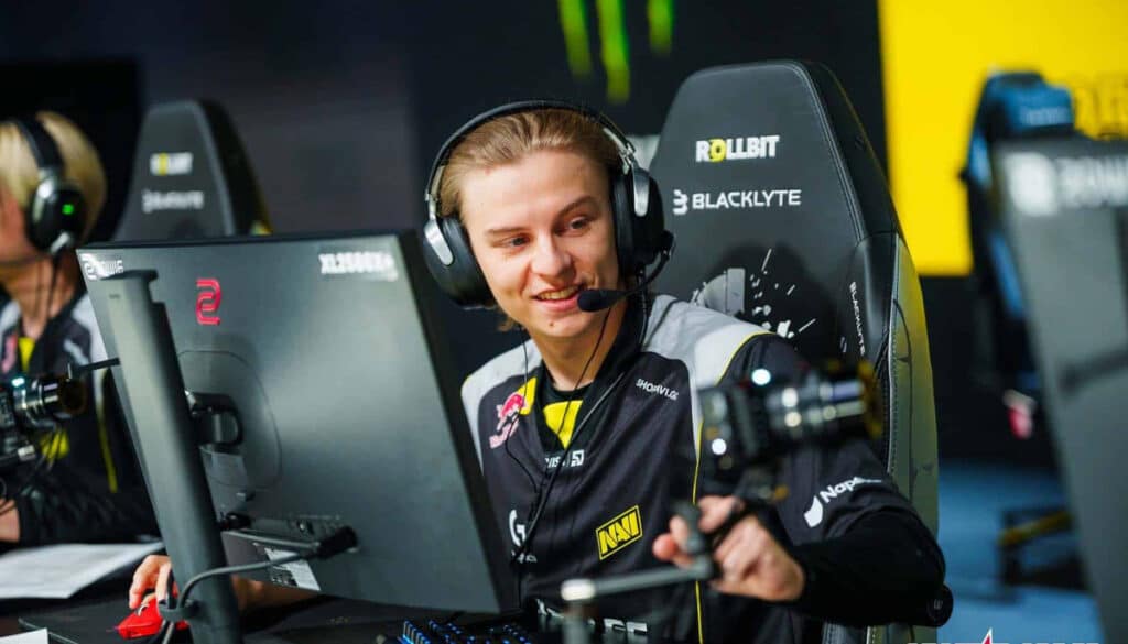 A NAVI esports player smiling at the desk during a CS2 match at the Budapest Major