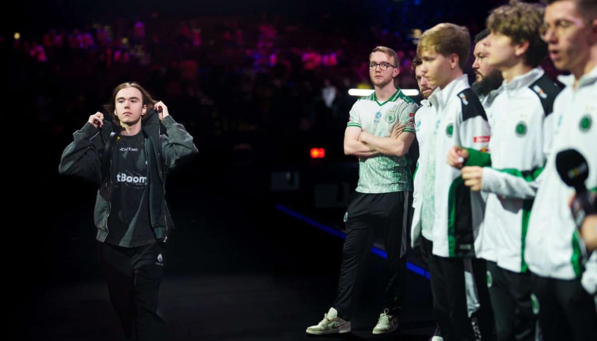 Donk walks confidently backstage in a dimly lit esports event, wearing a black jacket