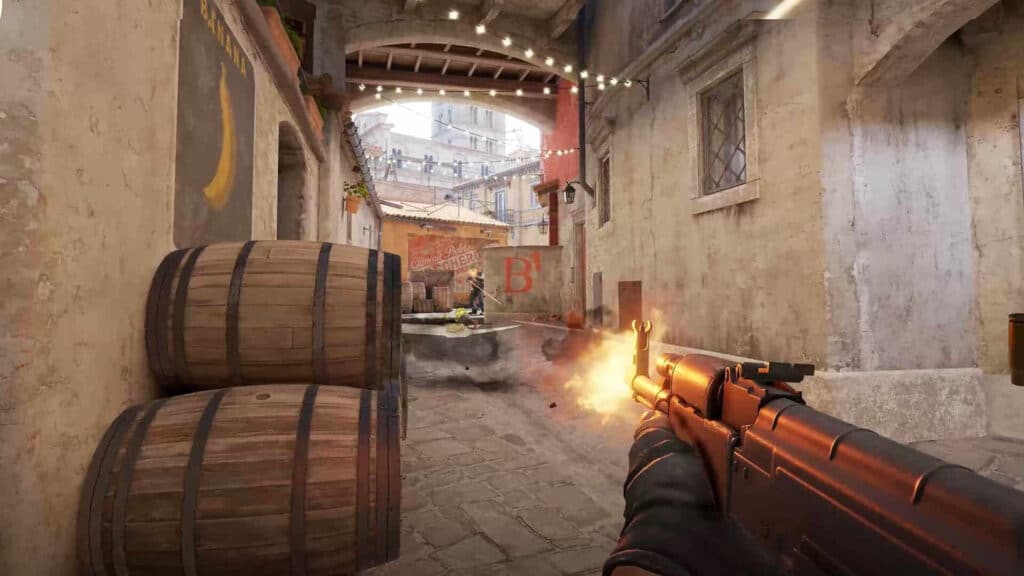A first-person view of a player in the tactical shooter game Counter-Strike 2, firing an AK-47 assault rifle in the "Banana" area of the Inferno map