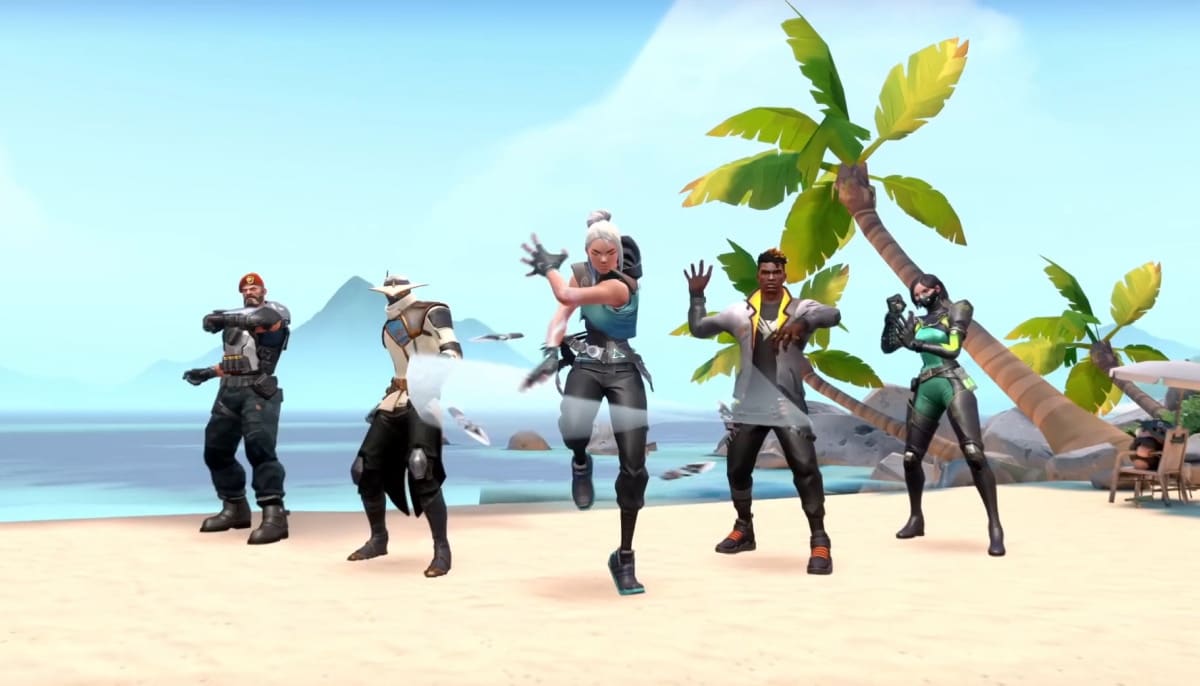 Five Valorant agents, including Brimstone, Cypher, Jett, Phoenix, and Viper, are dancing together on the sunny, tropical beach map named Breeze, surrounded by palm trees and mountains in the background