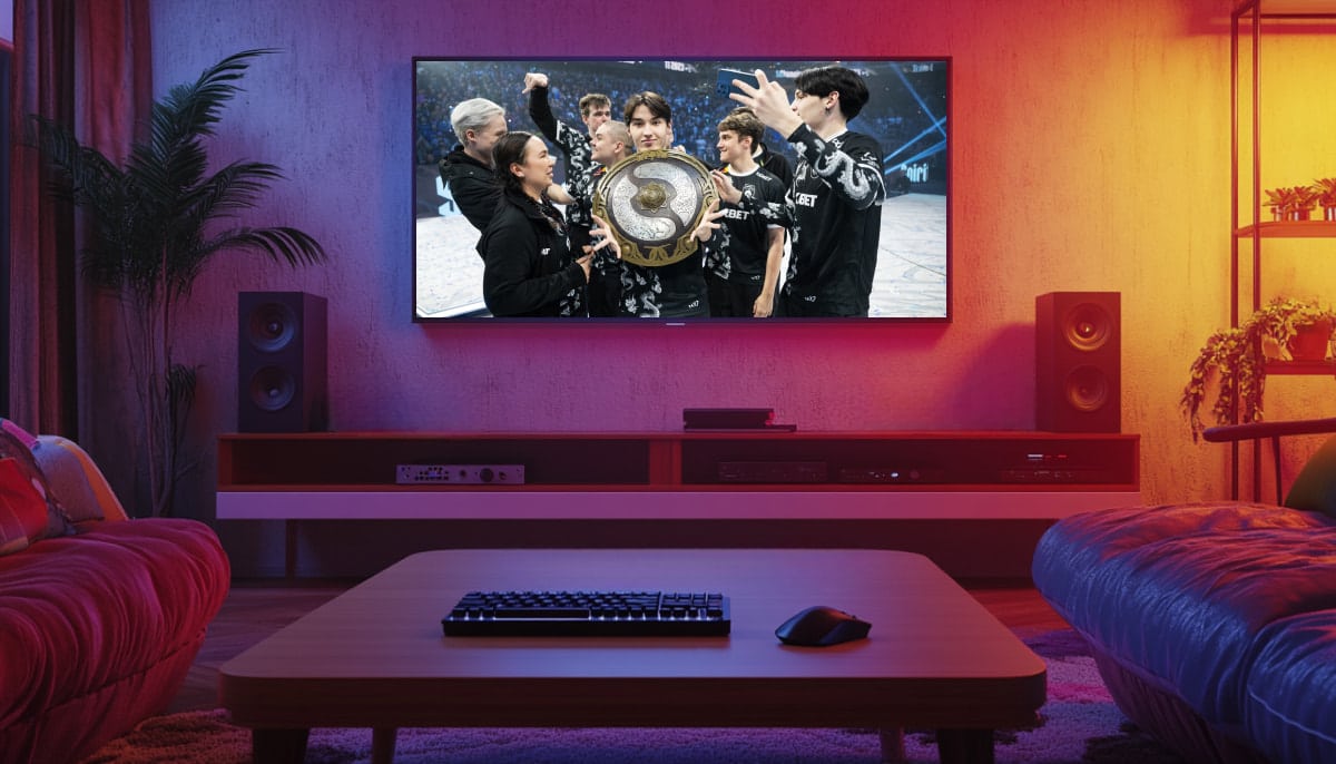 A living room with a large TV displaying the victorious Dota 2 eSports team, Team Spirit, holding the Aegis of Champions trophy after winning The International 2023