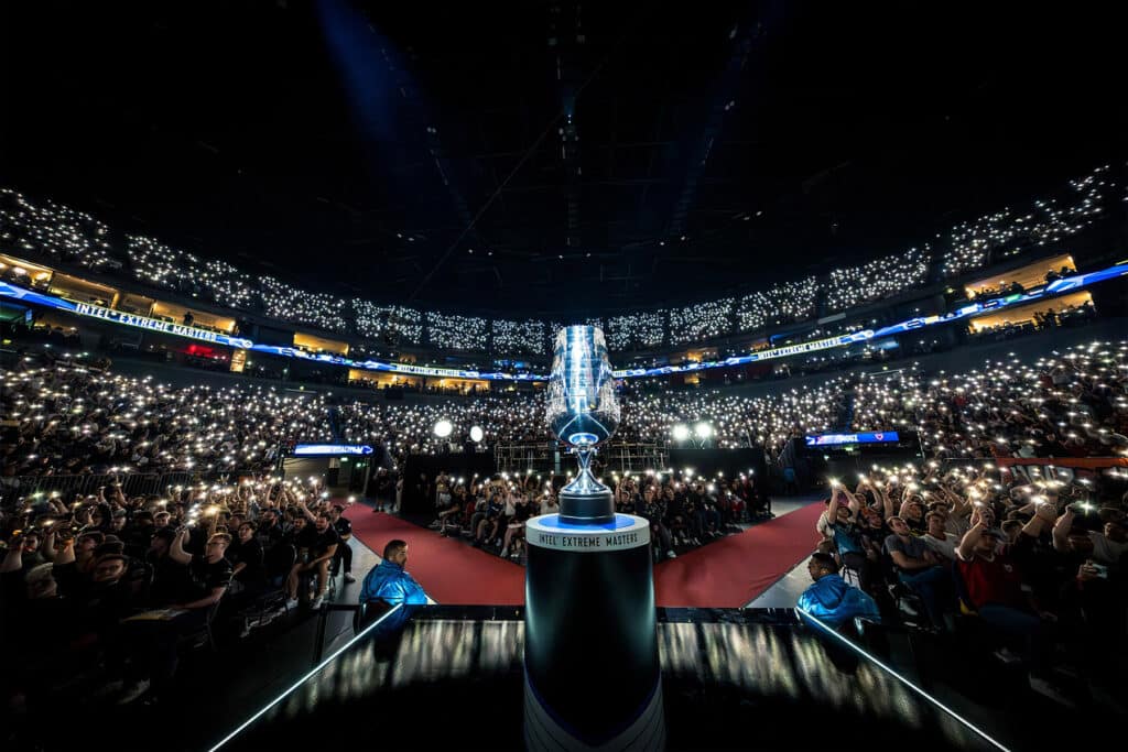 Image of IEM Cologne trophy on a platform with fans lighting up arena in background