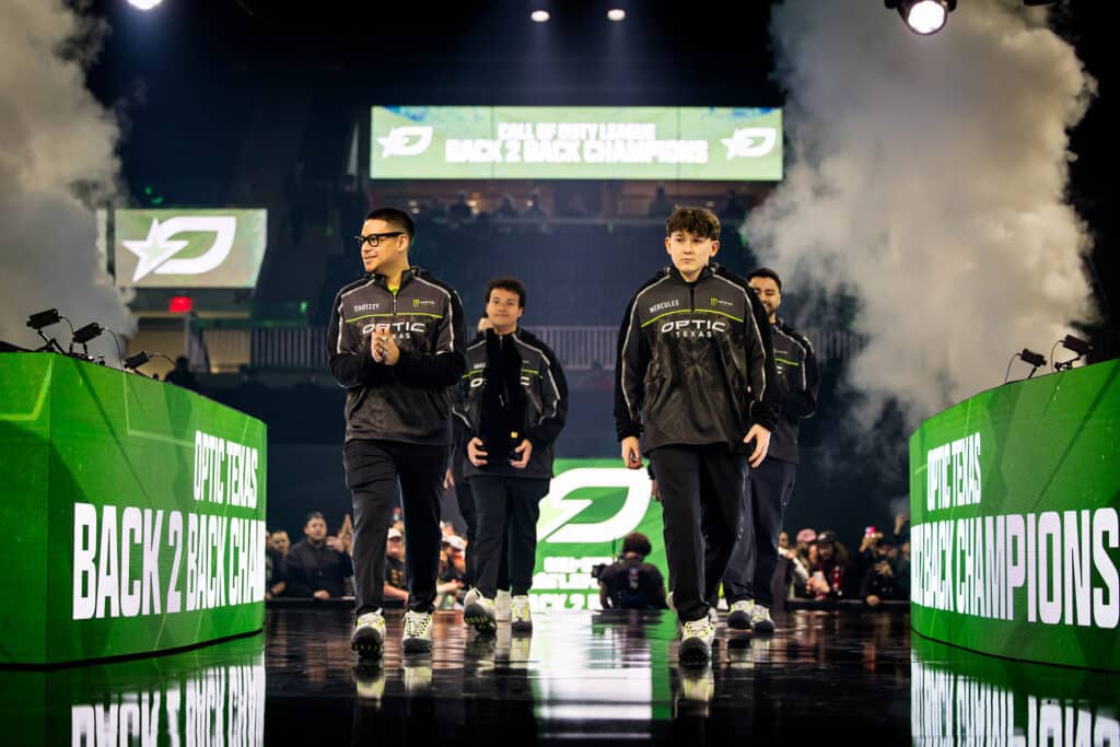 Image of OpTic Texas walking on stage while holding Call of Duty League trophy with a crowd in the background