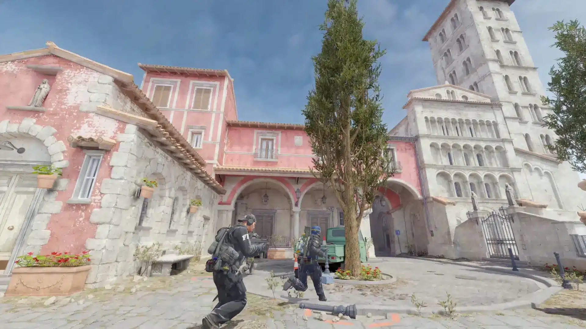 A first-person perspective of two Counter-Strike 2 operatives moving through a Mediterranean-style town square.